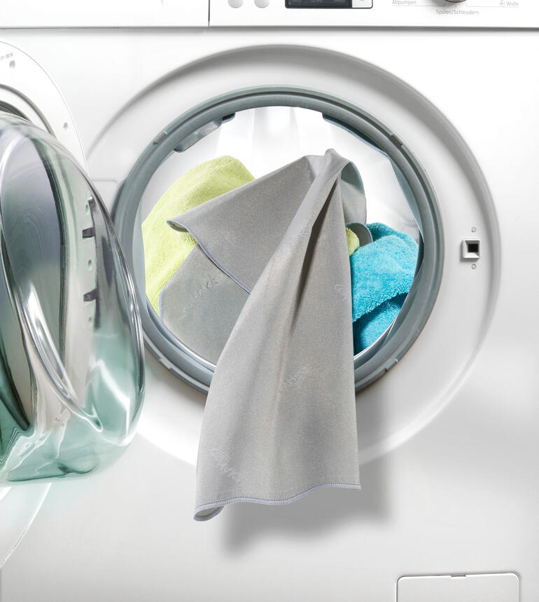 Aktivsilber beseitigt bis zu 99,9 % Bakterien auf Ihrer Wäsche. SilverWash®-Waschmaschinentuch hängt aus einer Waschmaschine mit bunten Tüchern
