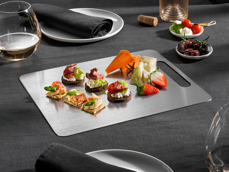 Ideal auch zum Anrichten und Servieren von Speisen. Titan-Schneidebrett mit verschiedenen Canapés auf einem Tisch
