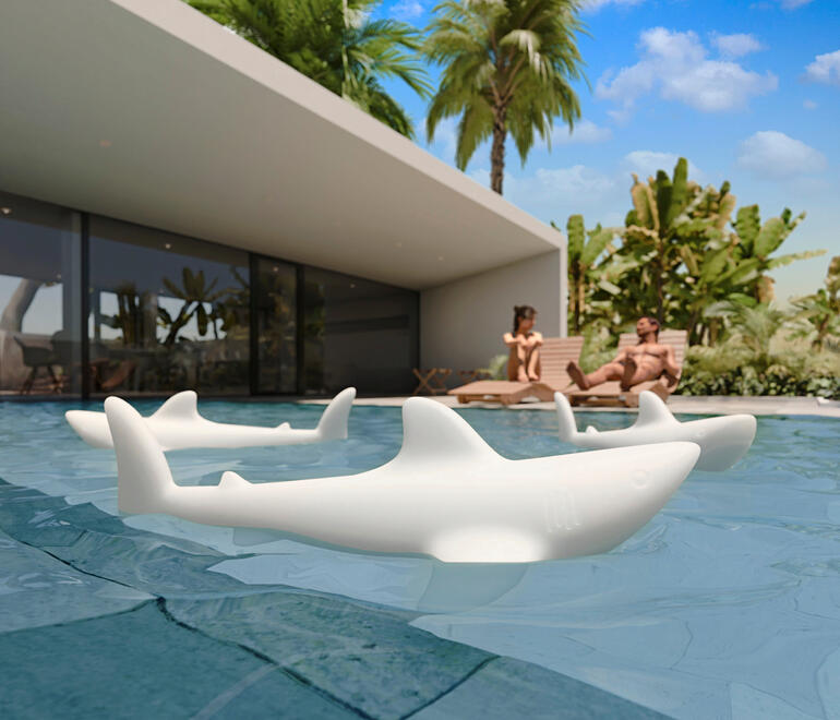 Auch am Tag ist der Hai aus transluzent weißem Kunststoff ein wahrer Blickfang. Weiße Hai-Leuchten schwimmen im Pool bei Tageslicht