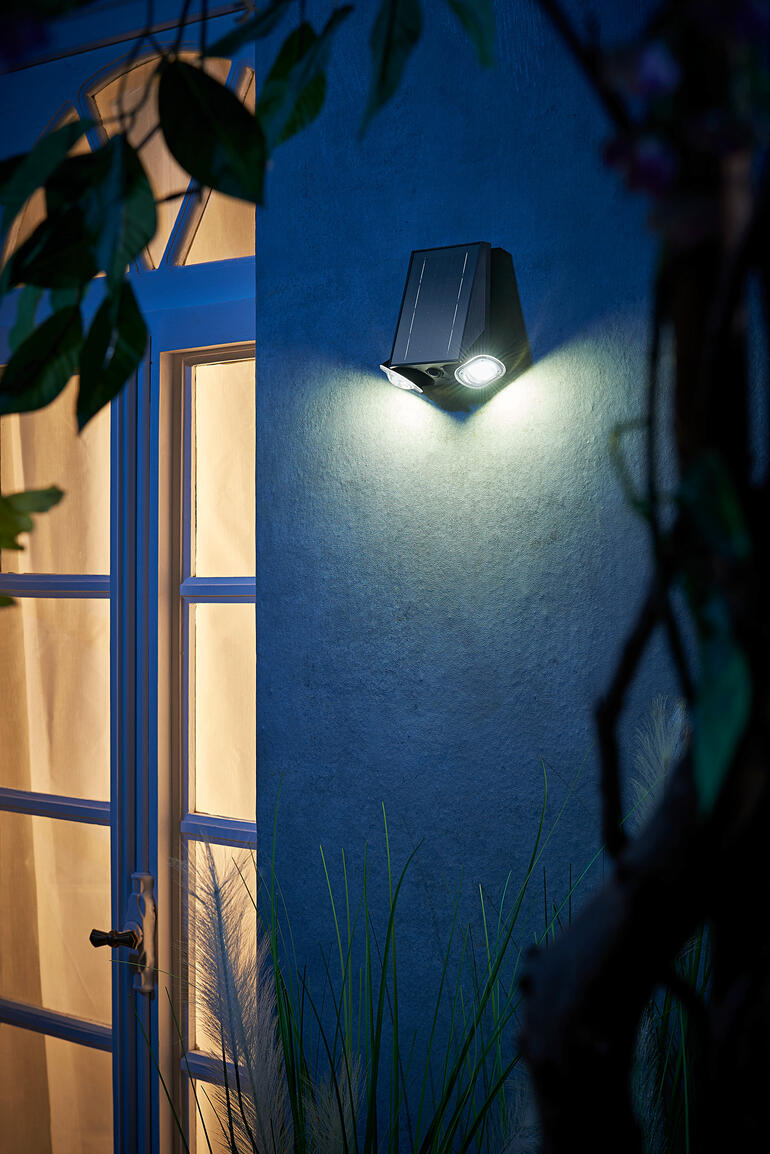 Intelligente Solarleuchte an einer Wand neben einer Tür bei Nacht