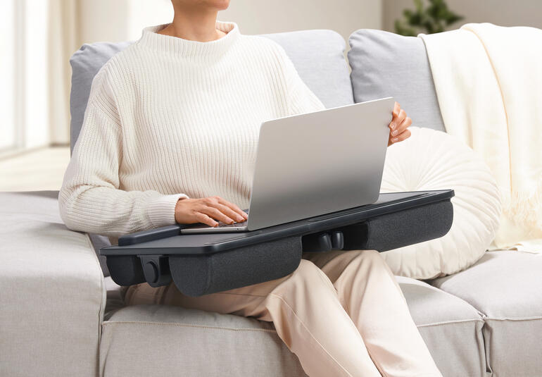 Person mit einem 2-in-1 Laptopkissen auf dem Schoß, das als Tisch dient.