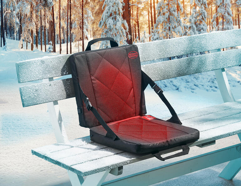 Beheizbare Sitzschale auf einer gefrorenen Parkbank im Winter.