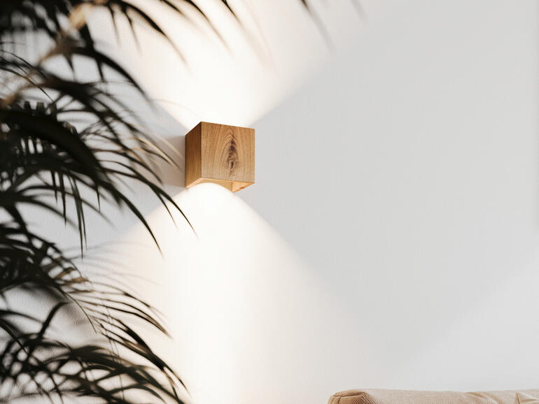 Wandleuchte Cubus, Eiche, an der Wand mit Pflanzen im Vordergrund