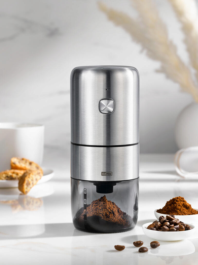 Akku-Kaffeemühle mit Edelstahloberfläche und Kaffeebohnenschale.