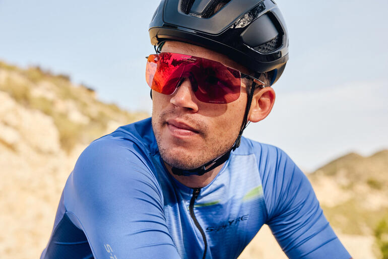 Radfahrer mit roter Sport-Sonnenbrille und schwarzem Helm auf einem Trail.