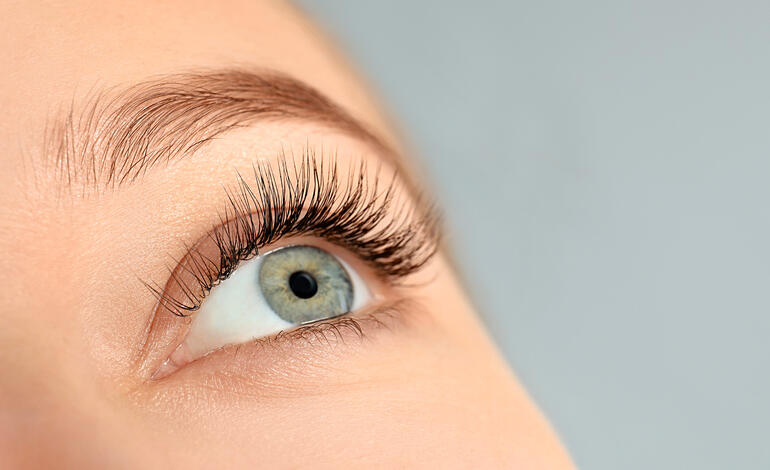Nahaufnahme eines Auges mit langen Wimpern, nach dem Auftragen des Wimpernserums.