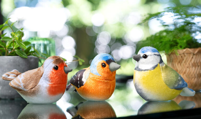 Drei dekorative Vogelfiguren in natürlichen Farben.