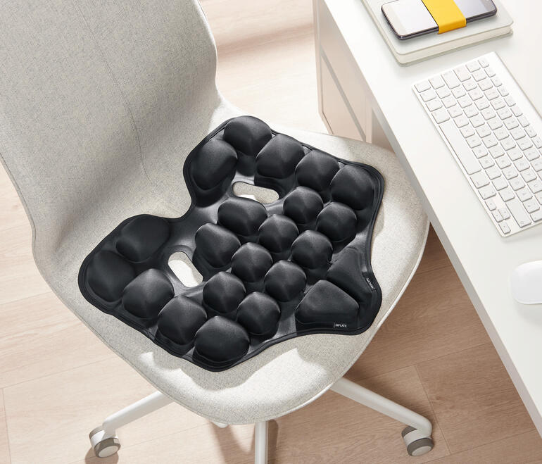 Schwarzes ergonomisches Sitzkissen auf einem Stuhl.