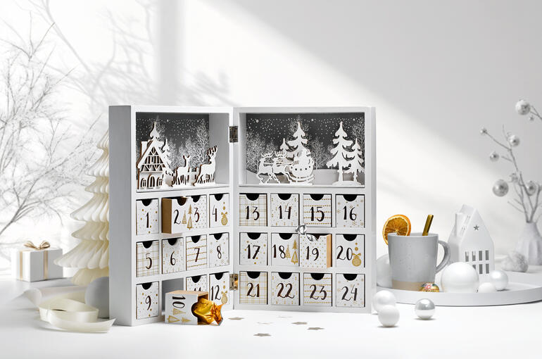 Adventskalender Winterdorf mit 24 Türchen und winterlicher Dekoration.