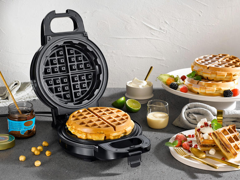 Extra tiefes Waffeleisen mit frischen Waffeln und Zutaten auf einem Tisch.