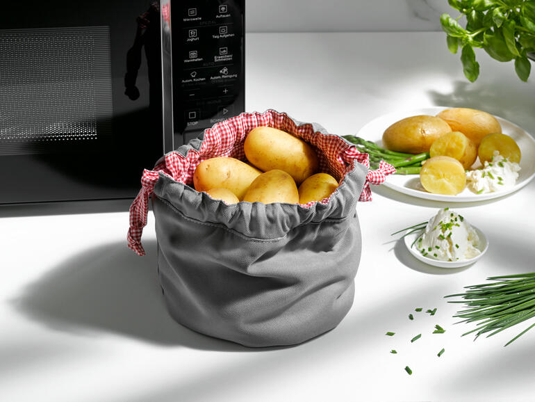 Grauer Kartoffel Garbeutel mit Kartoffeln und Kräutern auf dem Tisch.