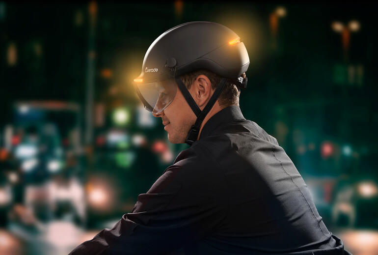Mann trägt einen Fahrradhelm mit Lichtsignal in der Stadt bei Nacht