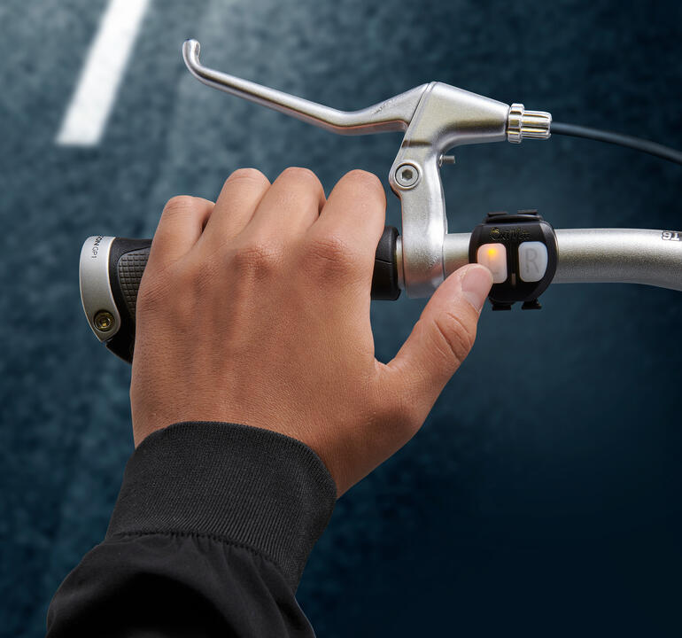 Lichtsignal-Fahrradhelm Hand drückt den Schalter für das Lichtsignal am Fahrradlenker