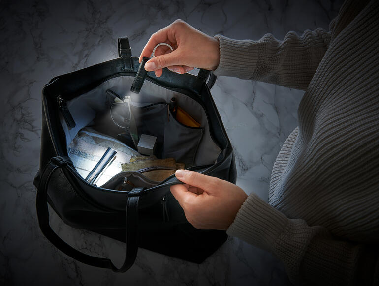 Zwei Hände halten eine smarte Mikro-Taschenlampe in einer Tasche