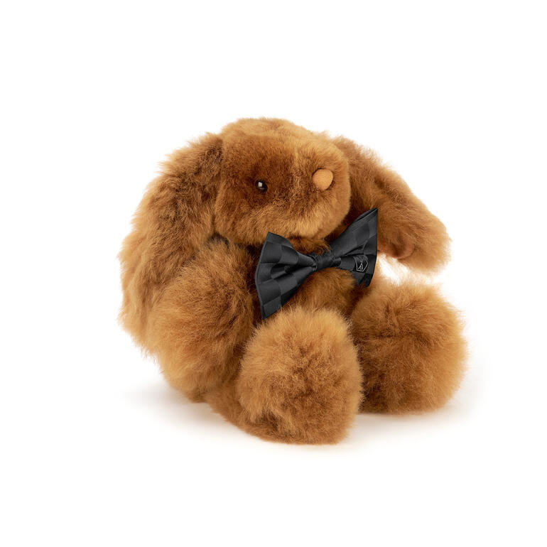 Kleiner, brauner Alpaka-Hase mit schwarzer Schleife auf weißem Hintergrund.
