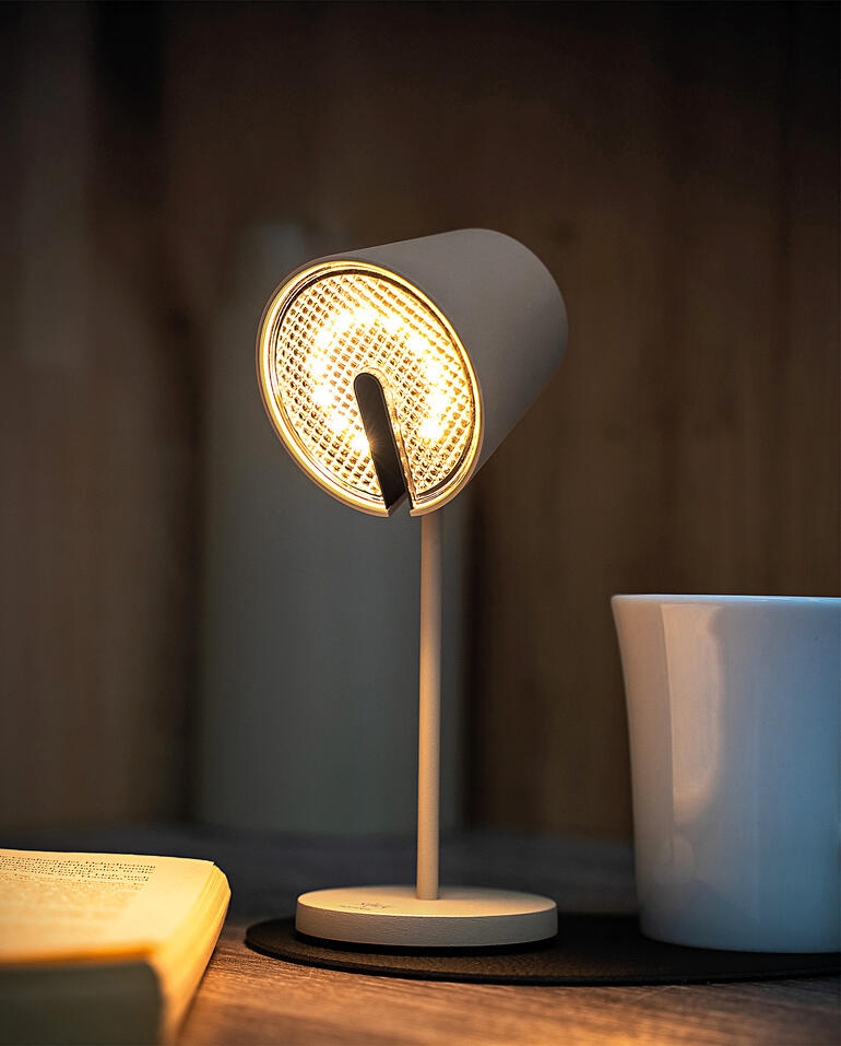 Schwarze Magnetleuchte mit hellem Licht, steht auf einem Tisch neben einer Tasse.