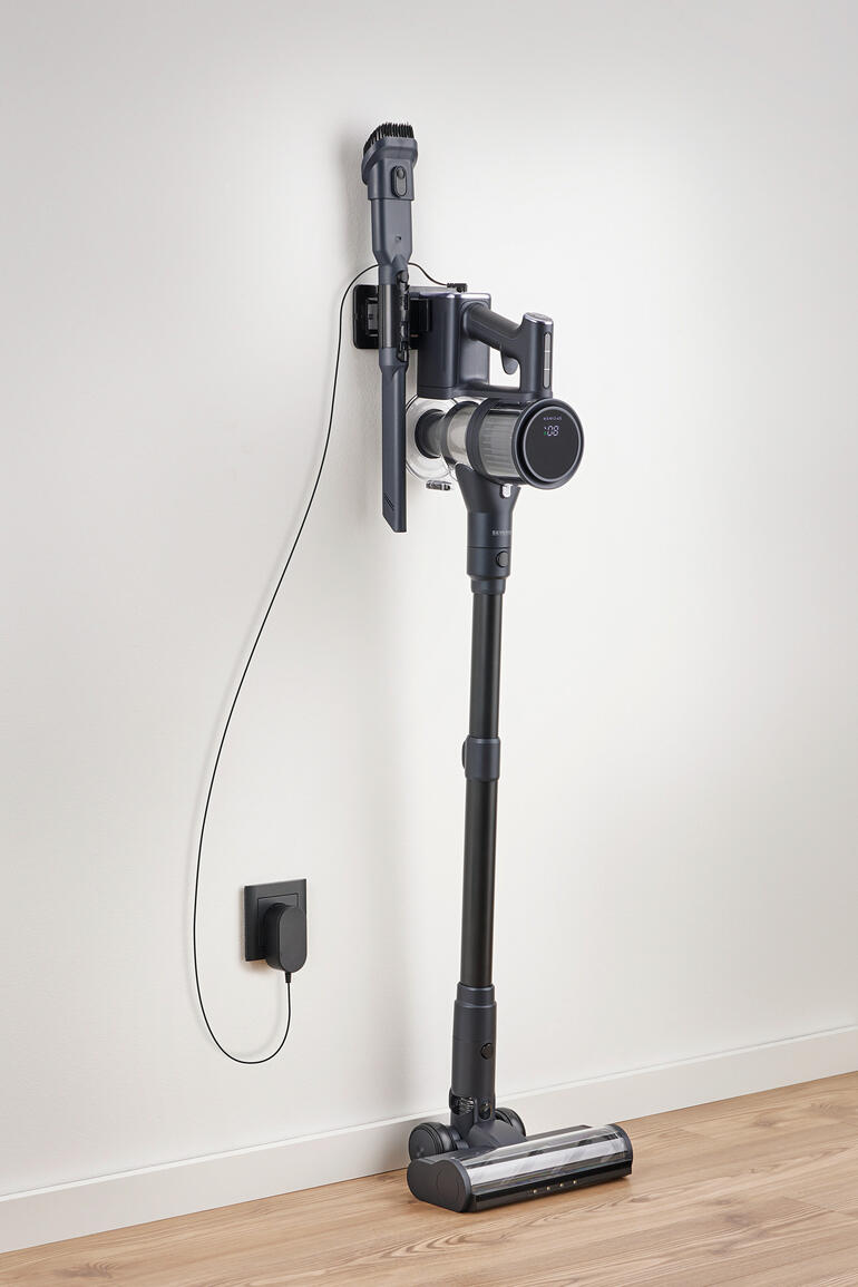 Akku-Staubsauger an der Wand montiert, mit Ladegerät.