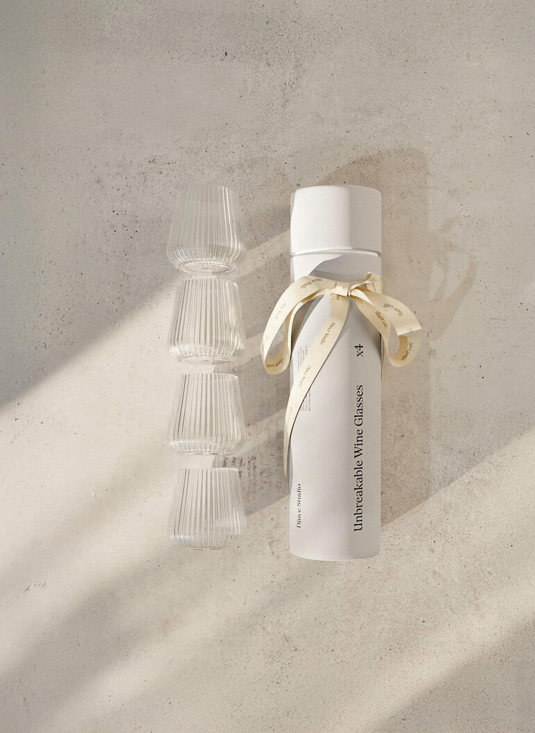 Flasche mit vier bruchsicheren Gläsern, dekorativ verpackt mit Schleife