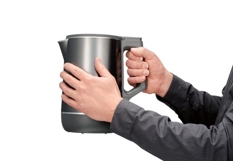 Benutzer hält den Doppelwasserkocher mit 3D-Heizsystem in der Hand.