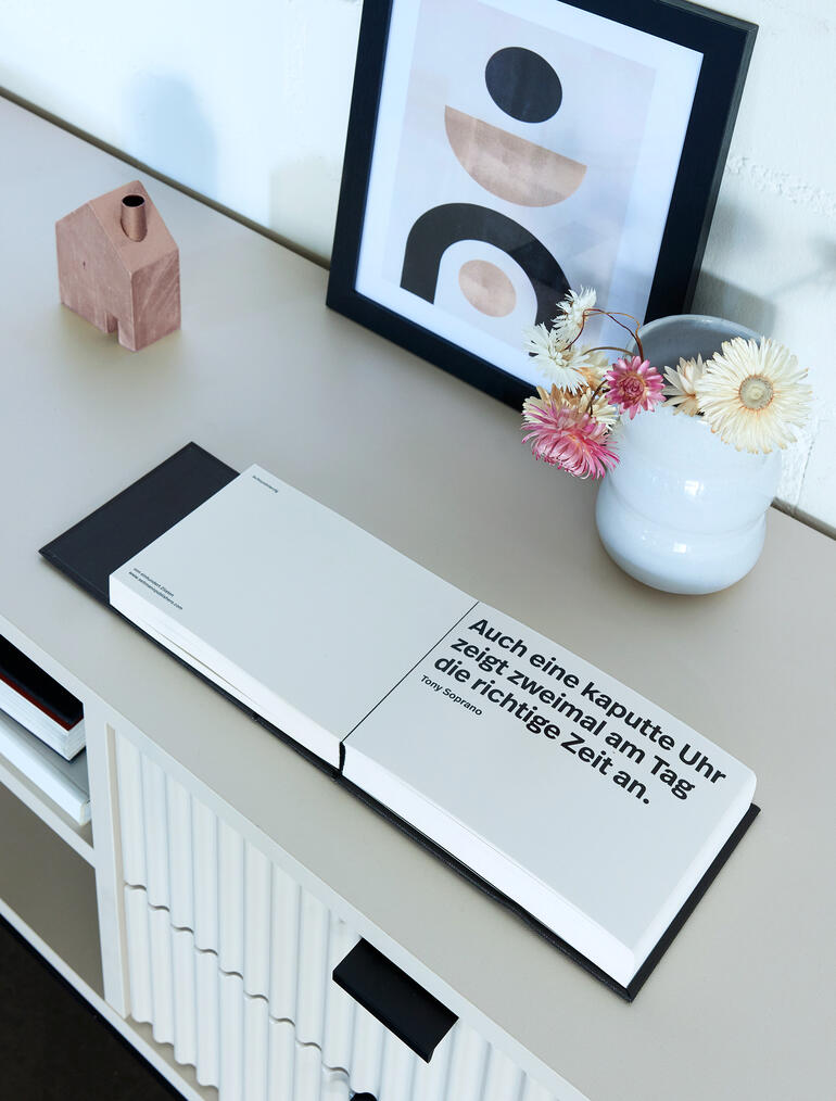 Buch mit Bahn-Trennblatt und Zitat auf einem Tisch.