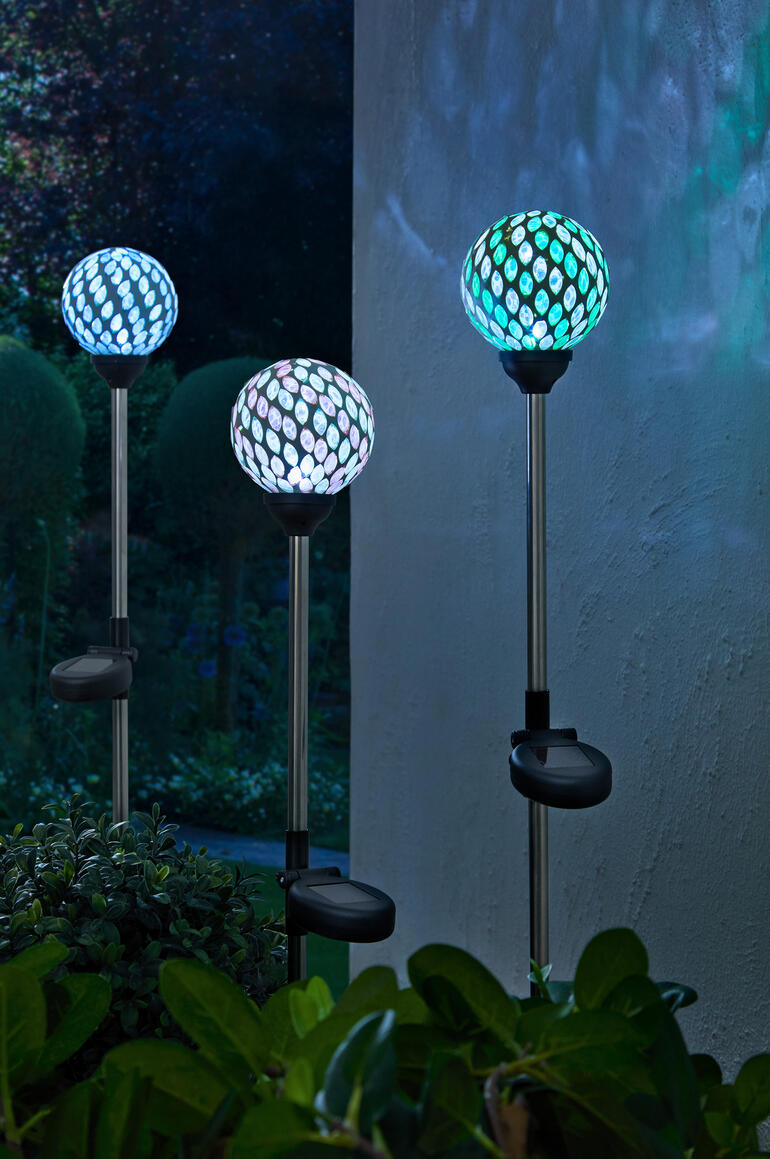 Drei Solargartenstecker mit bunten Mosaiklampen im Garten.