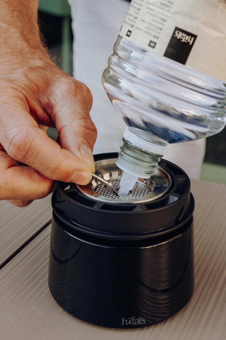 Mann füllt Bioethanol in einen Brenner mit einem speziellen Filter.