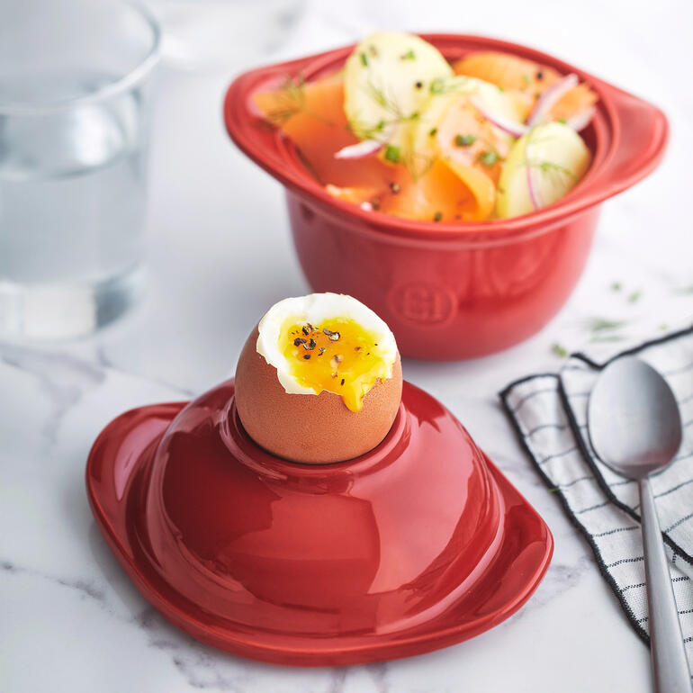 Roter Egg Coddler mit weichgekochtem Ei auf einem Tisch.