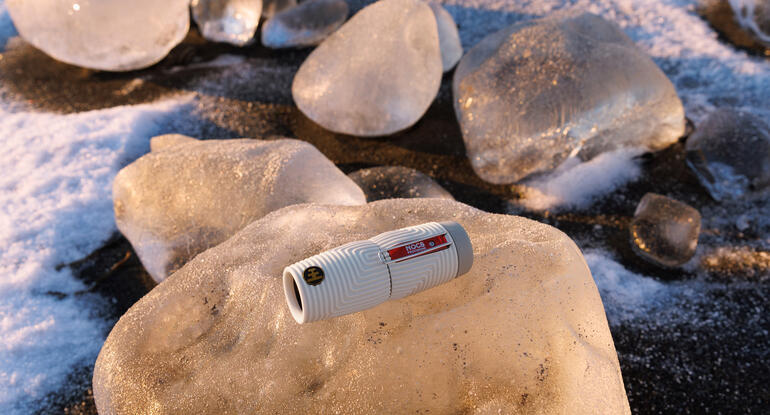 Nocs Provisions ZeroTube 10x25 Monokular auf einem Eisblock in einer Winterlandschaft.