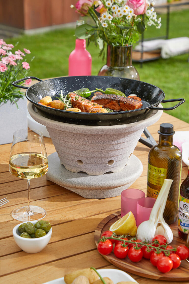 Bratfeuer mit Gemüse und Fisch auf einem Tisch im Freien.