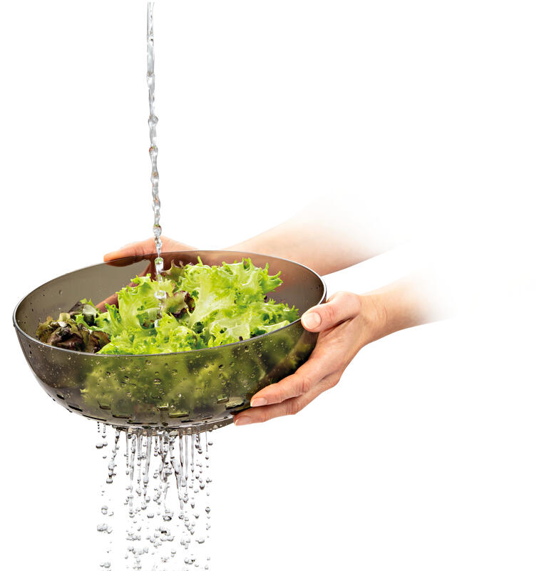 Grüner Salat wird unter Wasser in einer 3 in 1 Schale gewaschen