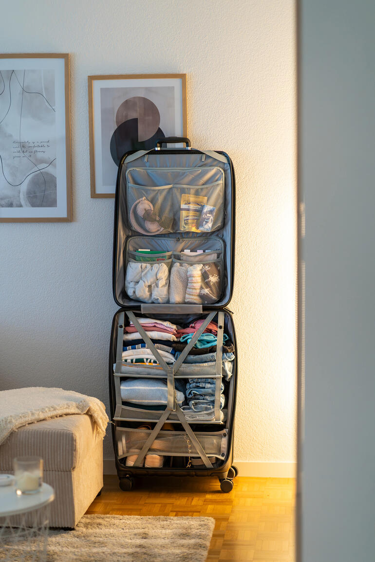 Schrankkoffer im Raum, ordentlich mit Kleidung gefüllt.