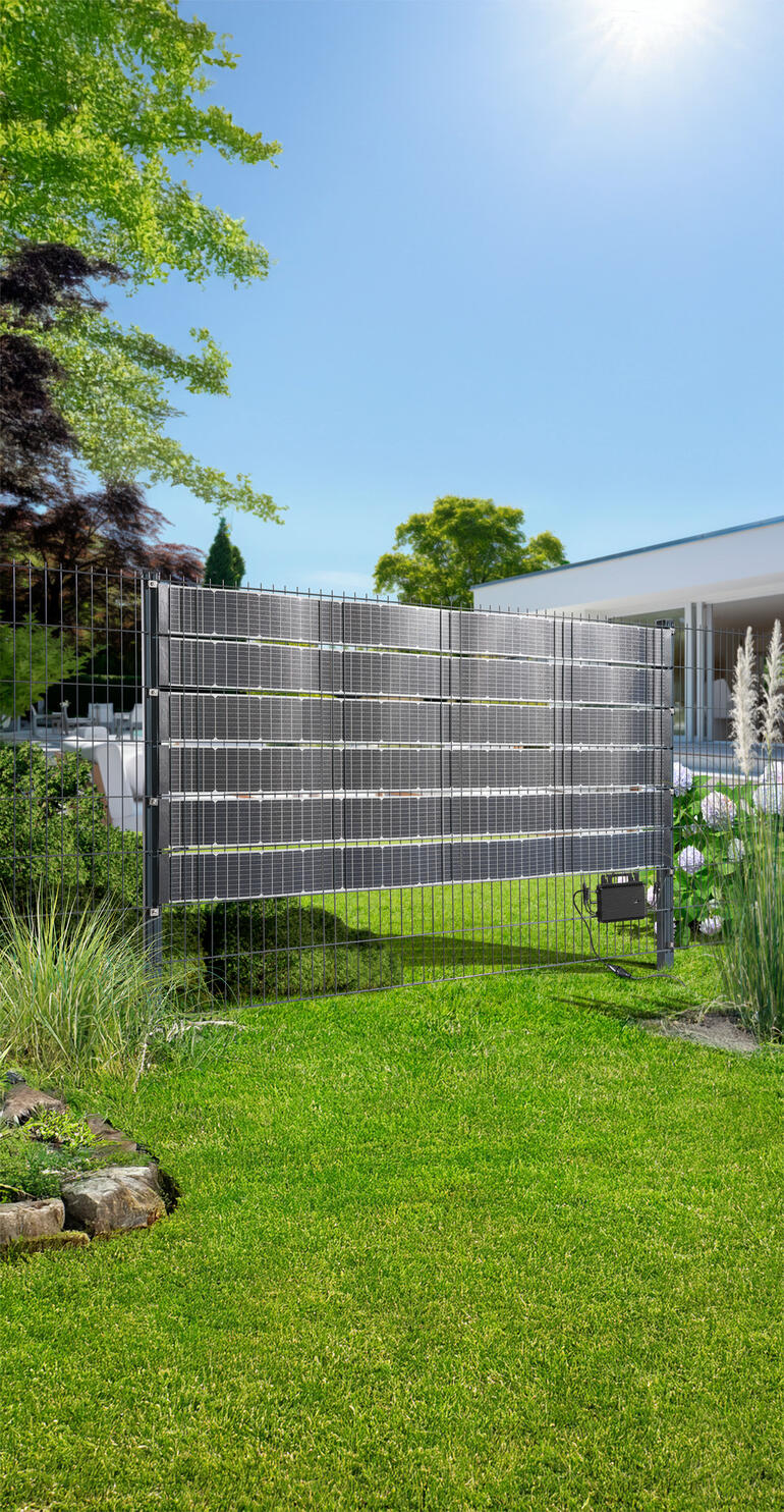 Solar-Zaunpaneel in einem Garten, das auf eine umweltfreundliche Energiequelle hinweist.