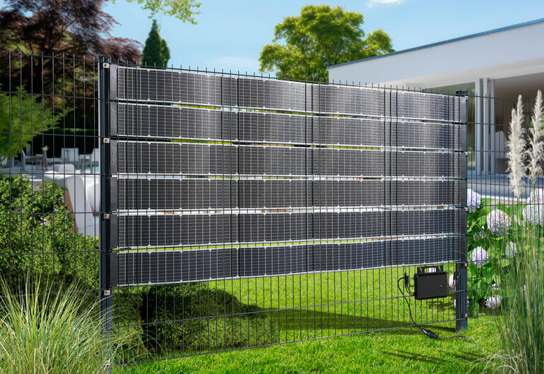 Solarkraftwerk eingezäunt mit mehreren Solarpanelen im Garten.