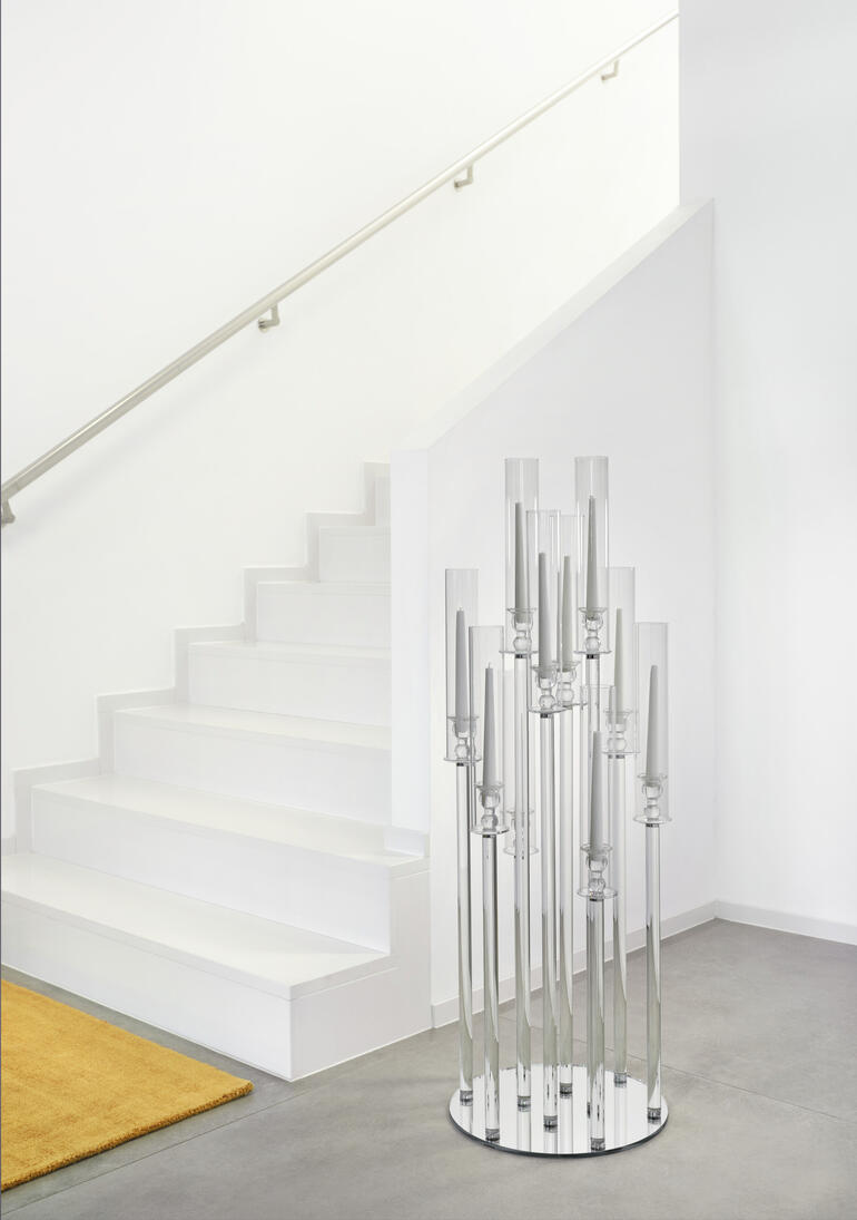 Hohes Windlicht aus Glas vor Treppe in heller Umgebung