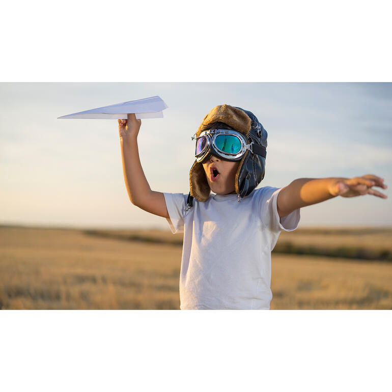 MyFirstJet Kind im Pilotenkostüm mit Papierflugzeug.