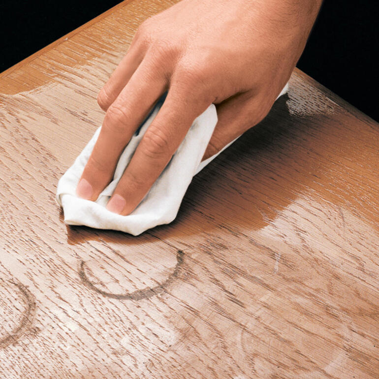 Eine Hand reinigt die Oberfläche eines Möbels mit einem Tuch