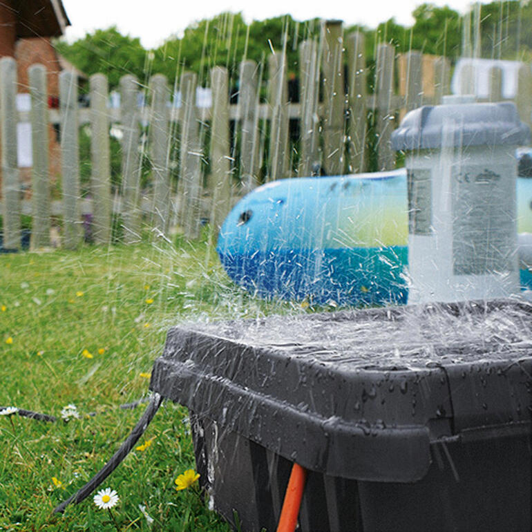 Mit der hohen Schutzklasse IP 55 ist die DRi®BOX 100 %ig staub- und regendicht. DRi®BOX wird von Spritzern Wasser getroffen auf einer Wiese.