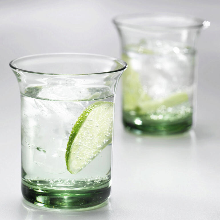 Zwei Goethe Wassergläser mit Eiswürfeln und Limettenscheiben auf einem Tisch.