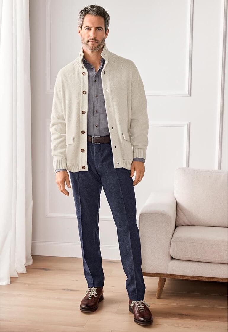 Royal-Alpaka Strickjacke Mann in einem grauen Royal-Alpaka-Strickjacke, steht in einem modernen Raum.