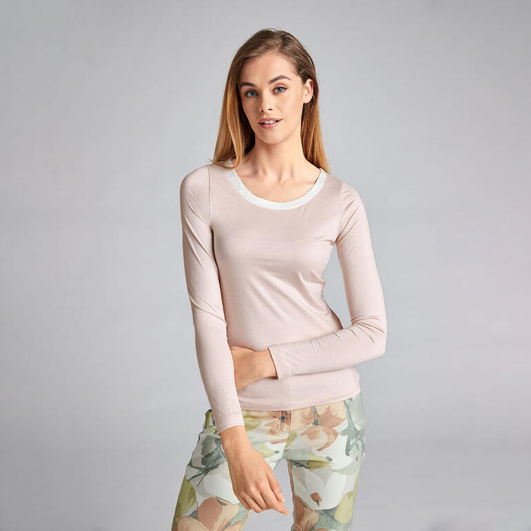 Rosé Frau in blassrosa Seiden-Edelshirt mit langem Arm und Rundhalsausschnitt.