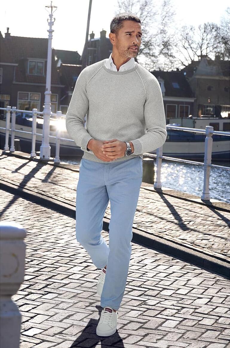 Grau/Weiß Mann trägt einen grauen Carbery Patentstrick-Pullover an einem Kanal.