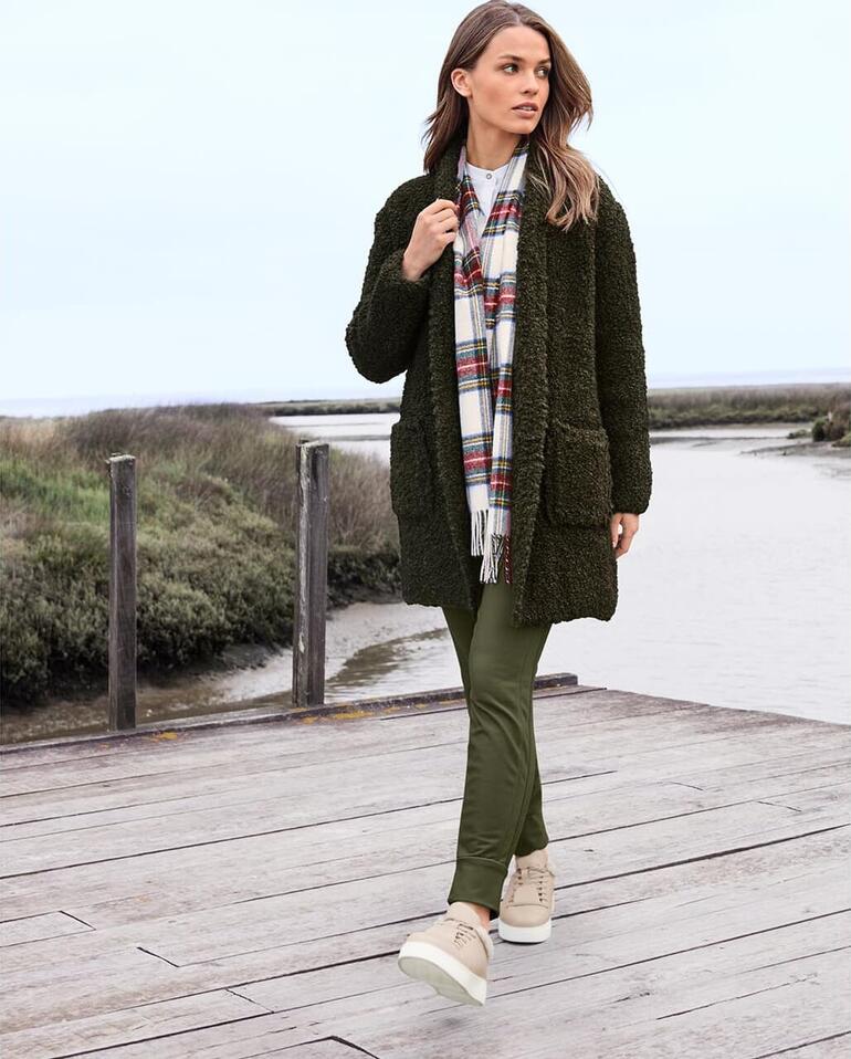 Graugrün Frau geht am Wasser in Stehmann City-Thermo-Jogger-Pants und Strickjacke.