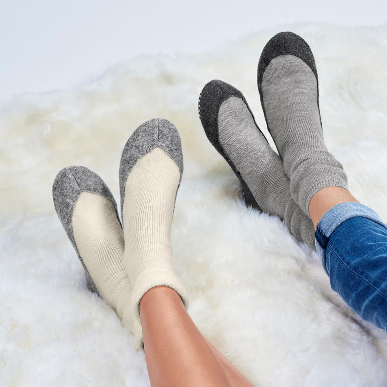 Füße in Hüttenschuhen mit grauer und beige Farbgebung.