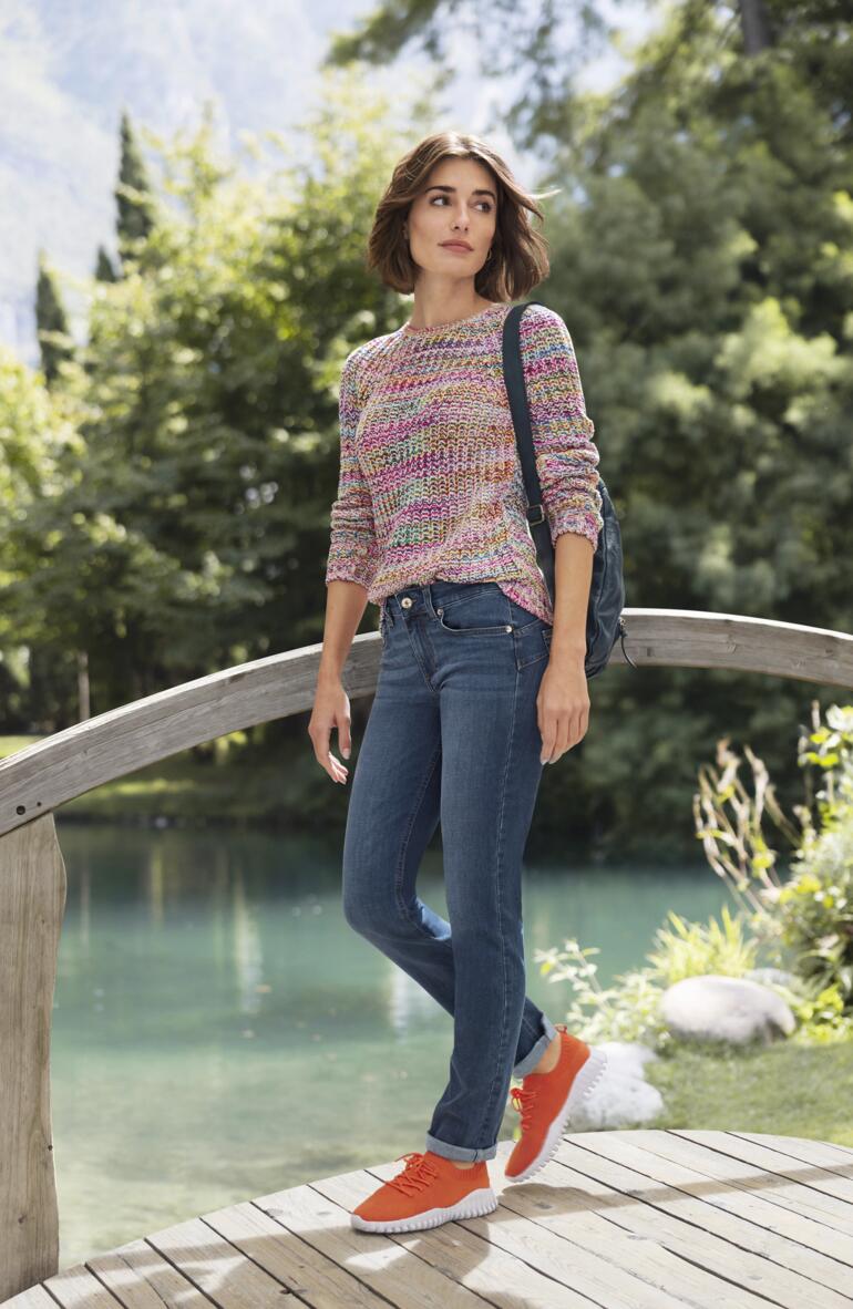 Liu Jo Jeans Bottom up, Slim Fit Frau in buntem Baumwollpullover auf einer Holzbrücke vor idyllischer Landschaft.