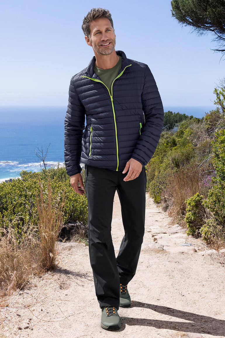 Herren Sommerdaunen-Jacke in navy, getragen von Mann in freier Natur mit Blick auf das Meer.