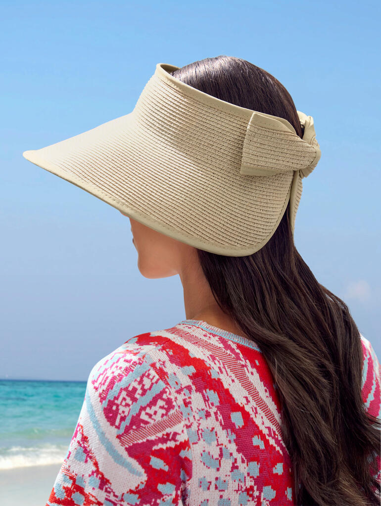 Loevenich Paper-Braid-Visor Frau mit Papier-Hut blickt seitlich auf den Strand.