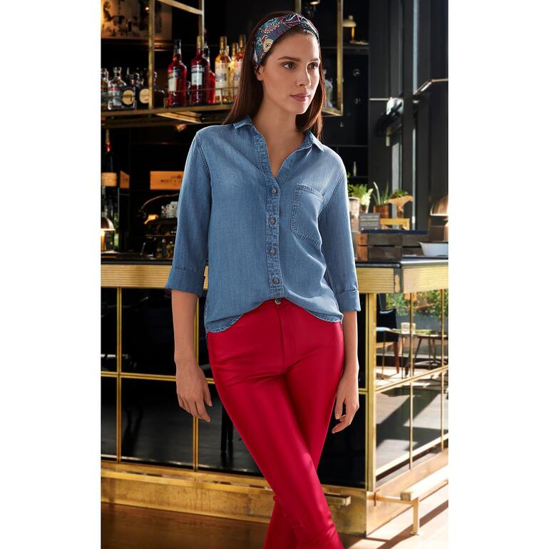 Eine Frau in blauer Jeansbluse und roten Leggings steht neben einer Bar.