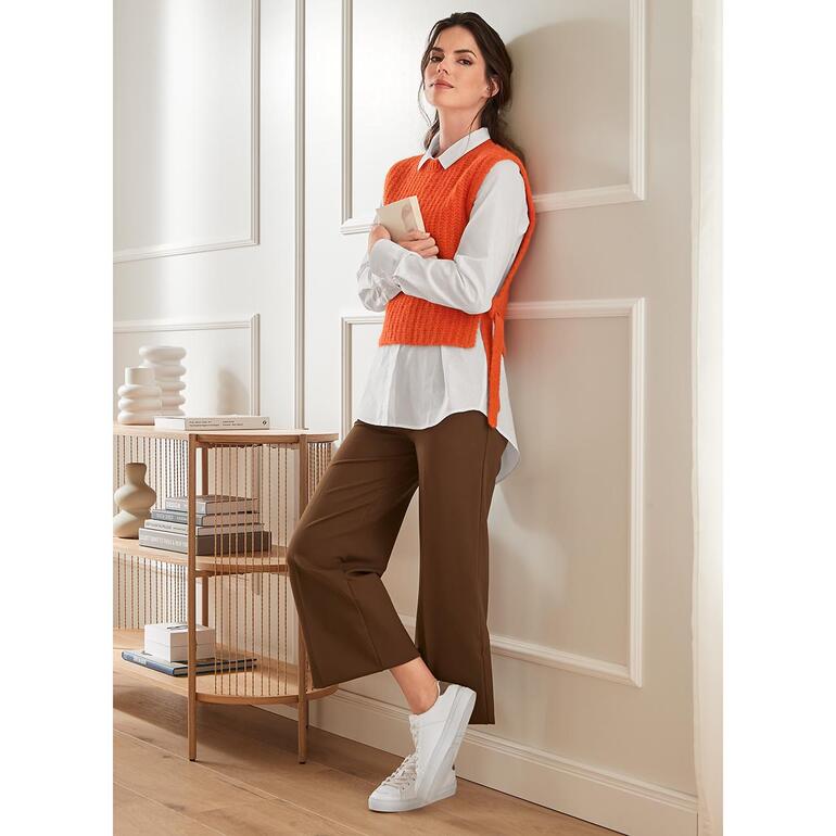 Orange Modische braune Weitbeinformhose mit weißen Sneakers, kombiniert mit einem orangefarbenen Pullunder.