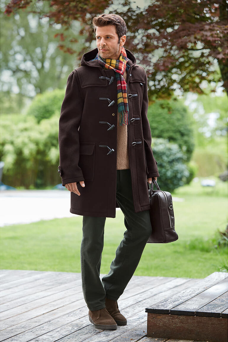 Gloverall Dufflecoat Mann trägt braunen Dufflecoat mit Tasche und Schal im Freien