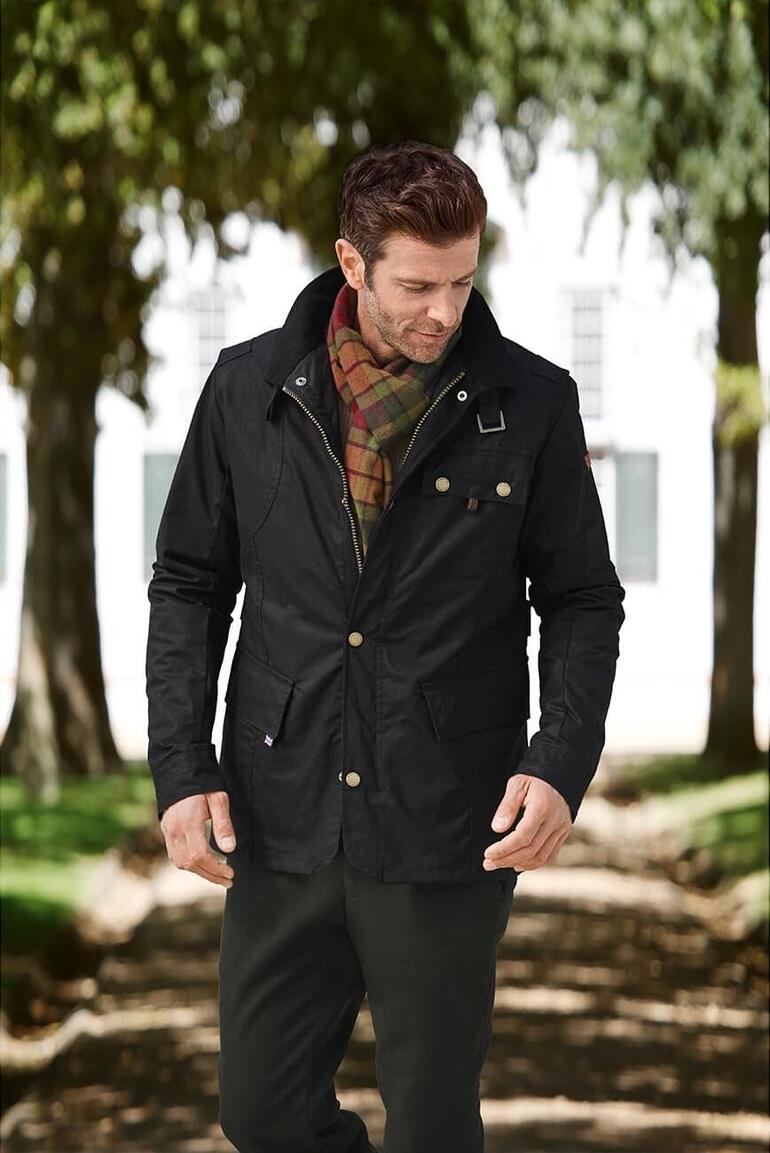 Mann in schwarzer Moleskin-Jacke mit Karoschal im Freien.